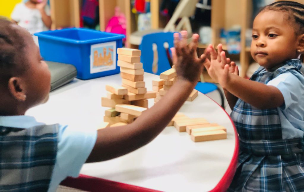 Preschool children in a classroom doing a high five